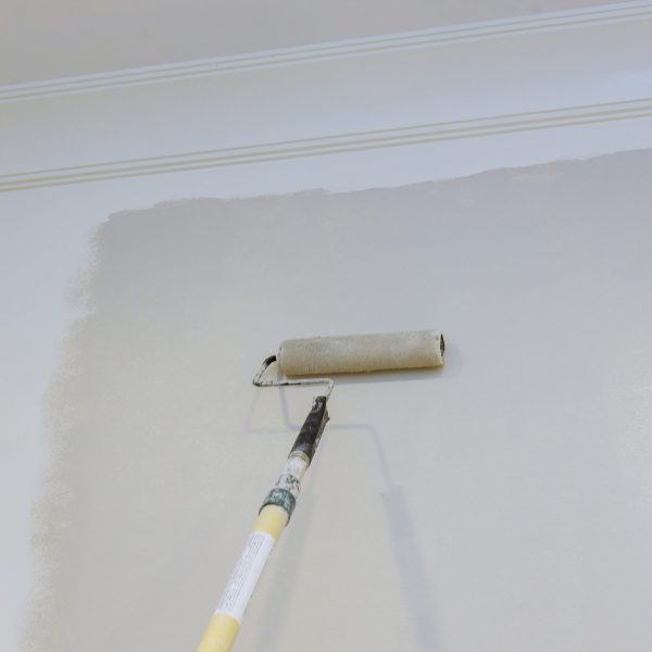 Renovation of interior, male hand painting wall with paint roller painting apartment, renovating with color paint